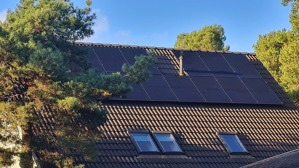 Photovoltaikanlage auf einem Berliner Hausdach mit Dachfenstern und Bäumen